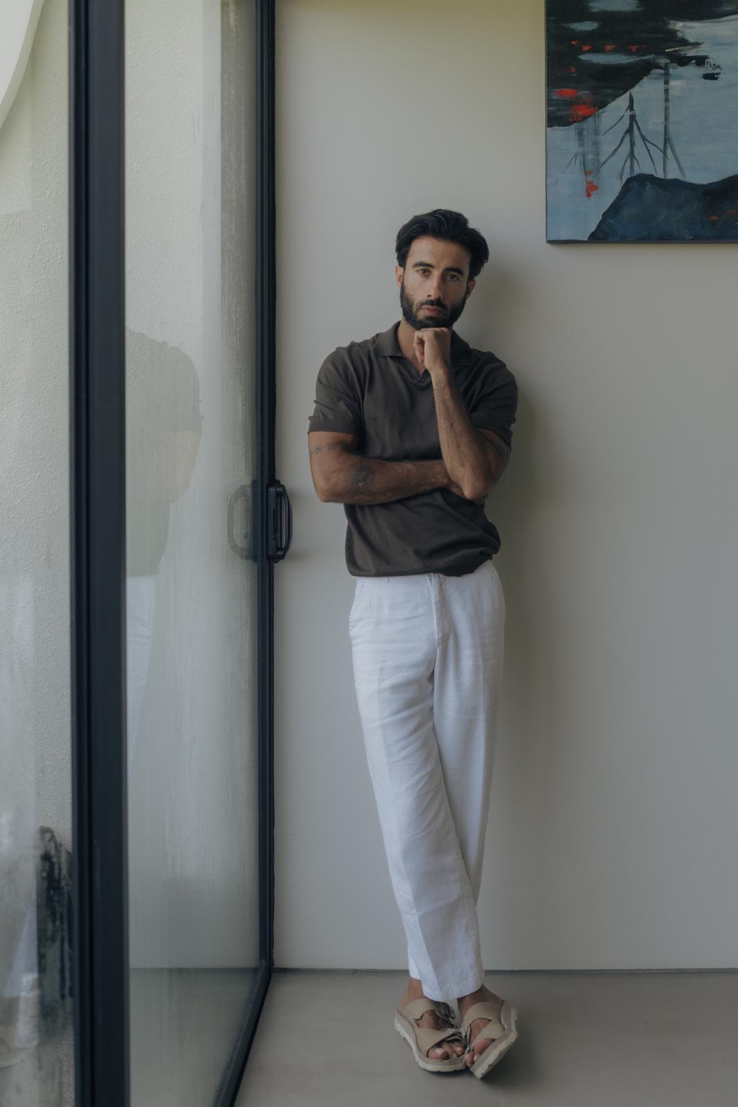 Suroesh Jazayeri standing by a glass door, hand at his chin.